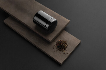 Blank tea black container packaging, with business card on black background with wooden elements,...