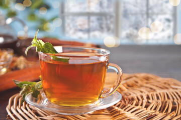 Cup of herbal mint tea with dry herbs on the tray.