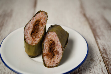 Red rice lontong or rice cake with spicy beef floss filling. Lontong or Rice cake is Indonesian dish made of compressed rice cake in the form of a cylinder wrapped inside a banana leaf then steam it.