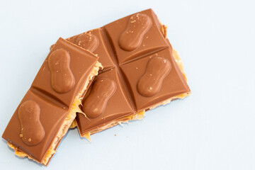 a piece of milk chocolate on blue background. unhealthy food, fats, sugar, sweets.