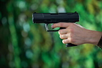Naklejka premium A woman holds a gun in her left hand. Close-up view.