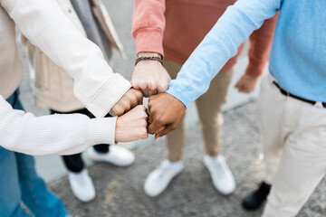 Close up hands of four multiracial people bumping their fists in city street - Young international group of friends making fist bump gesture together outdoors - Bump hand for team work concept