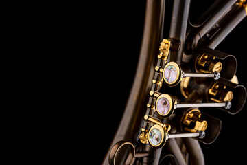 Naklejka premium A rotary type trumpet with a curved leadpipe in matte brown with gold elements and pearl type buttons on a black background
