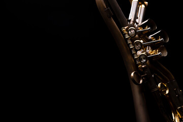 A rotary type trumpet with a curved leadpipe in matte brown with gold elements and pearl type buttons on a black background