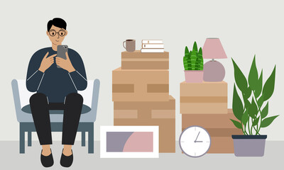 A man at home with a mobile phone sits in a chair. The concept of online registration of delivery of boxes, goods and assistance in moving.