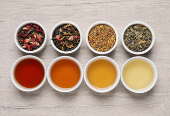 Flat lay composition with different freshly brewed teas and dry leaves on wooden table