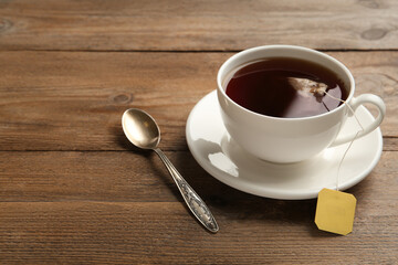 Tea bag in cup of hot water on wooden table. Space for text