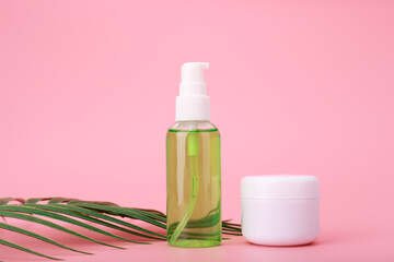 Fototapeta na wymiar Green cleaning gel for face and cosmetic jar with cream or mask on pink background with palm leaf