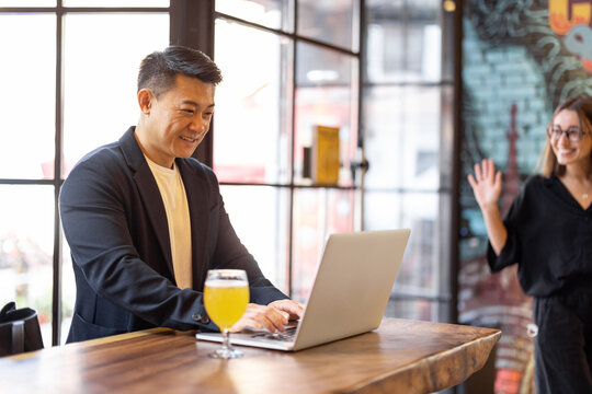 Multiracial Friends Or Business Partners Talking And Drinking Beer In Modern Pub. Concept Of Rest And Leisure. Business Deal While Drinking At The Bar. Pleased Young European Woman And Adult Asian Man