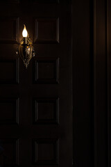Dark wall in the interior and one burning sconce in the old style. Wood wall