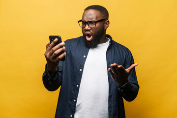 Shocked surprised African-American man staring at smartphone with wide open mouth isolated on...