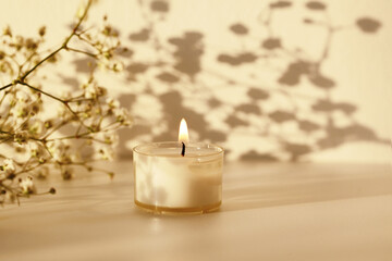 Obraz na płótnie Canvas Burning candle and gypsophila flower branch. Selective soft focus. Minimalist still life. Evening Light and shadow nature horizontal background.