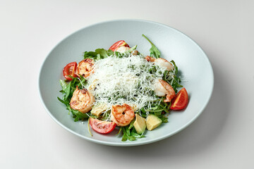 Diet salad with shrimps, avocado in a gray plate on a white plate