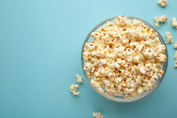 Popcorn in glass bowl on blue background.
