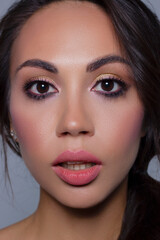 Fototapeta premium Beautiful brunet model woman face with brown eyes and perfect make-up . Portrait of beauty young brunet girl with pink lips. Female face with clear skin close-up. Skincare