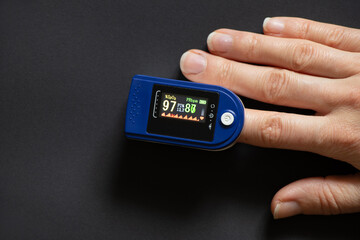pulse oximeter on the finger of a woman on an isolated background, measure the level of oxygen in...
