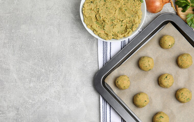 Raw falafel balls and ingredients on grey table, flat lay. Space for text