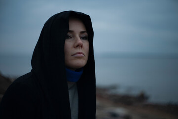 Sad woman sitting on stones by the lake