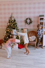 Children are holding gifts for Christmas Nearby is a Christmas tree In a pink room A surprise in a box with a bow for a holiday Waiting for a toy from Santa Claus