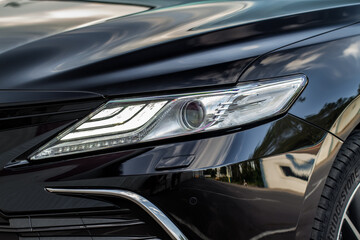 Fototapeta premium Headlight lamp of new cars. Close up detail on one of the LED headlights modern car. Exterior closeup detail. Closeup headlights of car.
