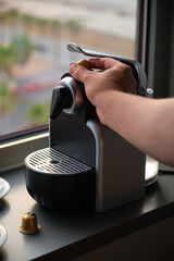 Hand preparing coffee in a coffee machine with capsules.