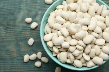 Bowl of uncooked white beans on blue wooden table, top view. Space for text