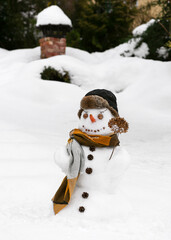 Cute smiling snowman with warm hat and long scarf in the winter garden. Having fun in wintertime....
