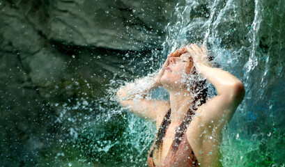 beautiful young cute sexy redhead woman under the splashing water shower waterfall in the Spa...