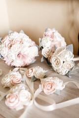 Beautiful stylish Bridal peonies bouquet Bridesmaids bouquet of white and pink peonies lies on the table Fresh peonies boutonnieres with beige ribbons Beige background  