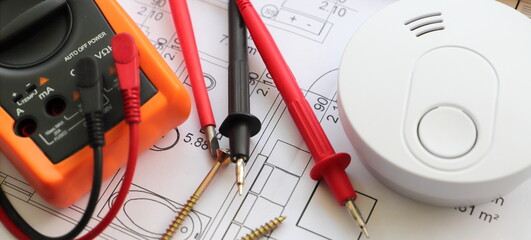 smoke detector with a screwdriver and a measuring device on a circuit diagram