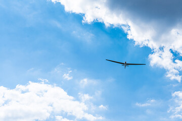 Glider flies elegantly through the dramatic clouds.