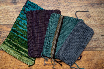 Top view of knitted swatches yarns on brown wooden background.