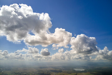 Aerial view from airplane window at high altitude of earth covered with white puffy cumulus clouds.