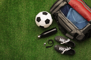 Gym bag and sports equipment on green grass, flat lay. Space for text