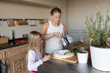 Mother with daughter child  preparing sweet dessert cream cake in home kitchen