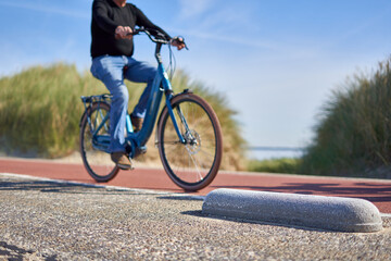 Male cyclist dressed in jeans and sweater, riding across a bike path in the Netherlands.