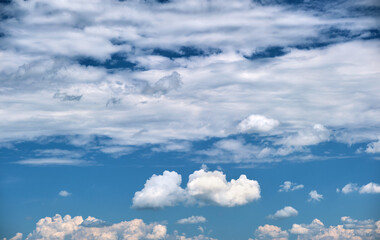 Bright landscape of white puffy cumulus clouds on blue clear sky.