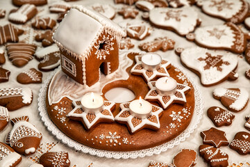 Advent candlestick with three lighted candles and christmas homemade gingerbread house