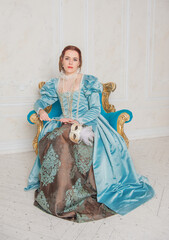 Beautiful young woman in medieval style blue dress with mask