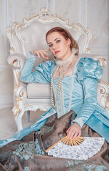 Beautiful young woman in medieval style blue dress sitting on the floor