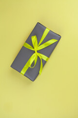 Gift packed in ultimade gray on a yellow background. The trend colors are yellow, gray. Copy space. View from above.
