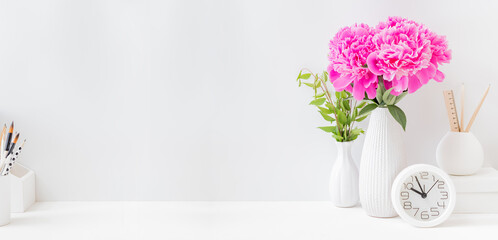 Home office desktop with pink peonies in a vase on a light background