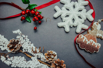 Pine cones, red ribbon and christmas decorations on dark background