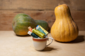 Spools of colorful thread in a coffee cup with pumkins