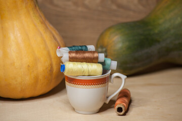 Spools of colorful thread in a coffee cup with pumkins