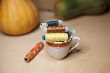 Spools of colorful thread in a coffee cup with pumkins