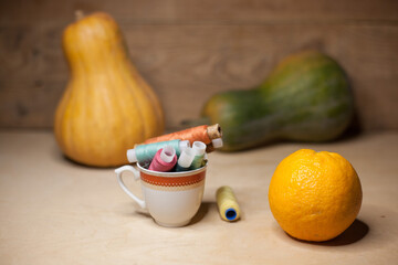 Spools of colorful thread in a coffee cup with pumkins