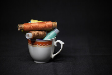 Spools of colorful thread in a coffee cup