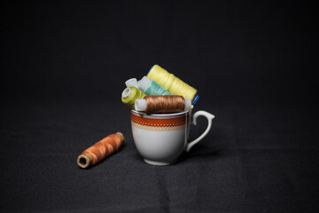 Spools of colorful thread in a coffee cup