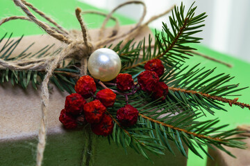 Close-up of a Christmas gift wrapped with a spruce branch and beads.